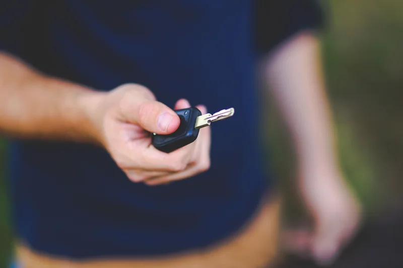 A person holding a car key outdoors