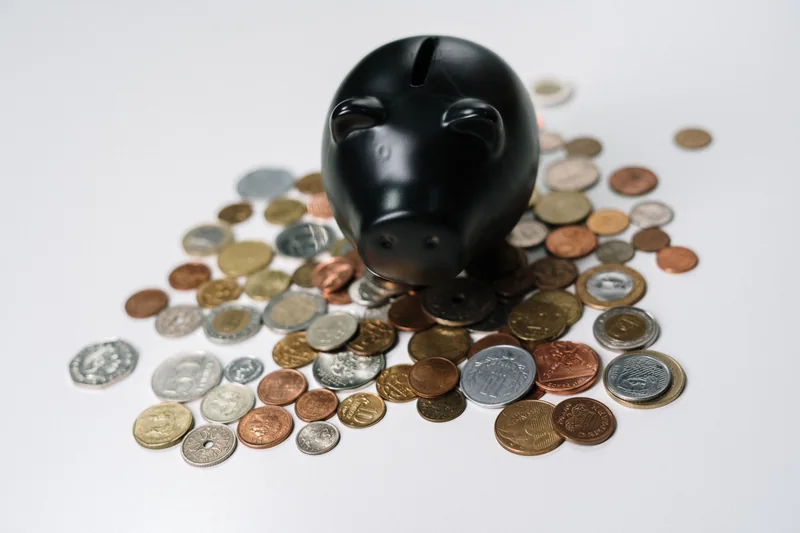 A black piggy bank surrounded by coins
