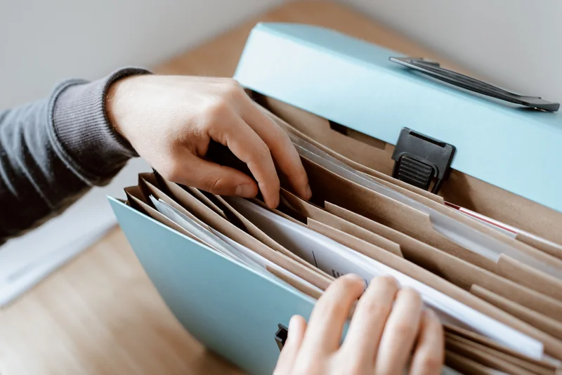 Hands organizing documents in a blue briefcase