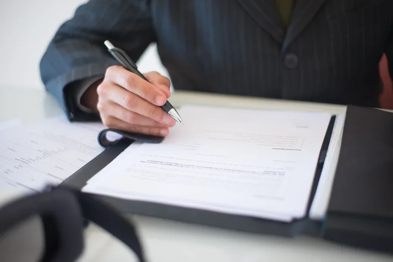 A person signing paperwork with a pen
