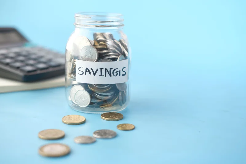 A savings jar and calculator on a blue tabletop