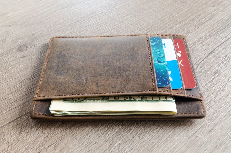 A leather wallet holding US cash and cards
