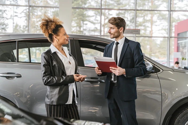 Customer discussing a car purchase with a dealer in a showroom