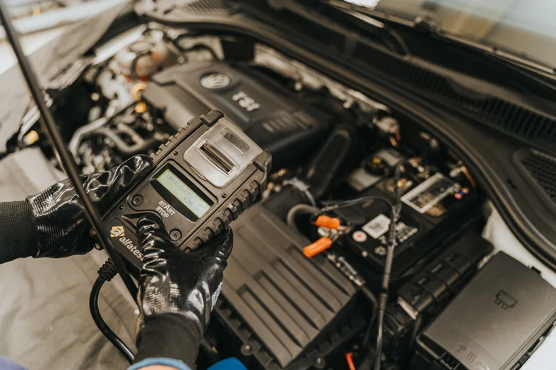 Mechanic using diagnostic equipment under the hood