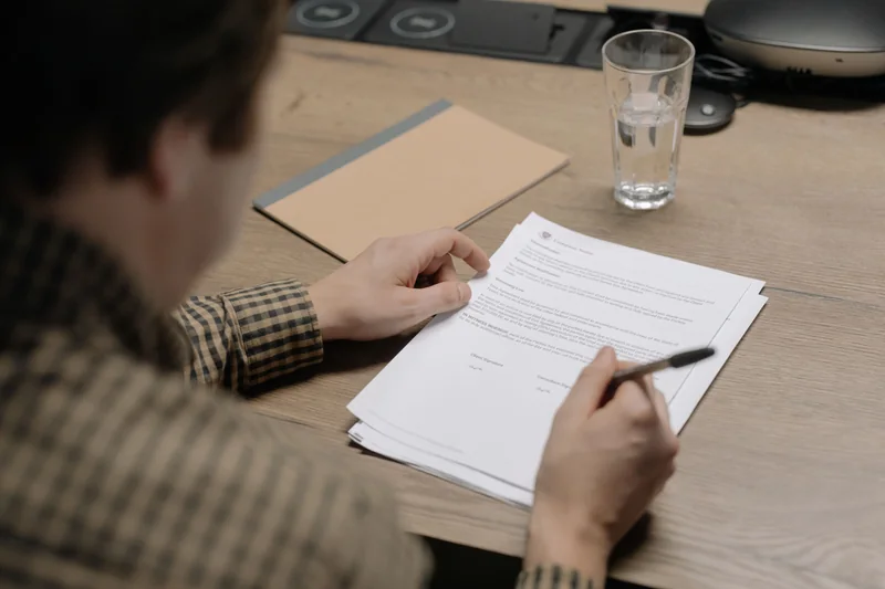 A person reviewing paperwork with a pen