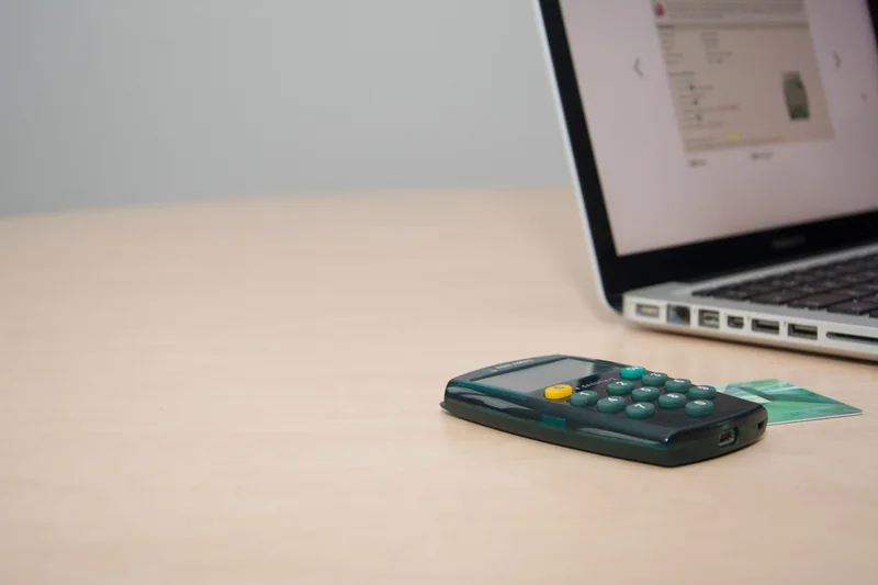 A calculator and card beside an open laptop