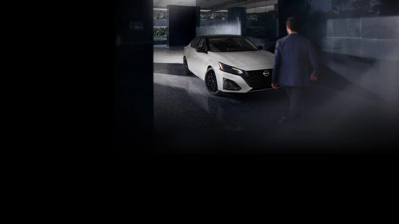 White Altima beside a pedestrian in a shaded parking structure