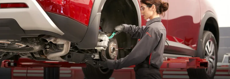 Nissan technician inspecting brakes with vehicle on a lift