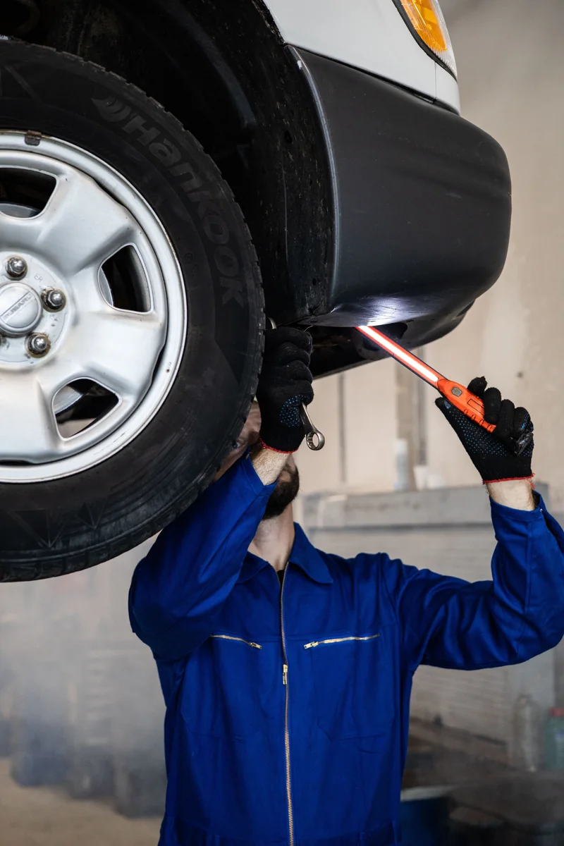 A mechanic inspecting a vehicle from underneath