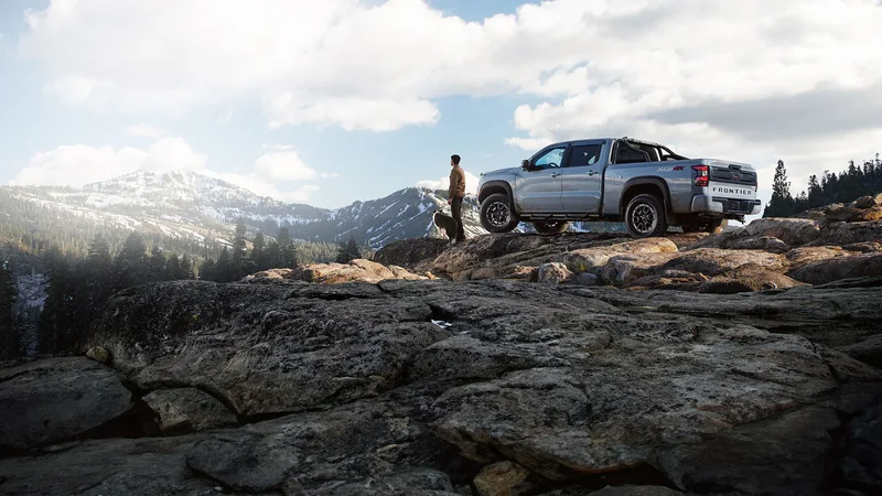 Gray Frontier parked on a rocky mountain outcrop beside a person