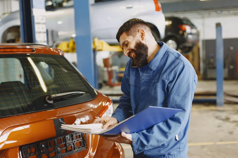 A mechanic recording a vehicle inspection on a clipboard