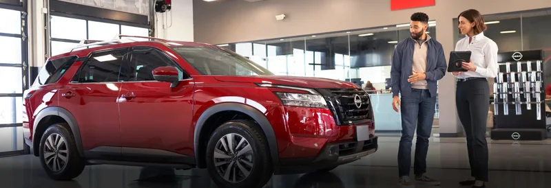 Nissan customer and service advisor beside a vehicle in a service bay