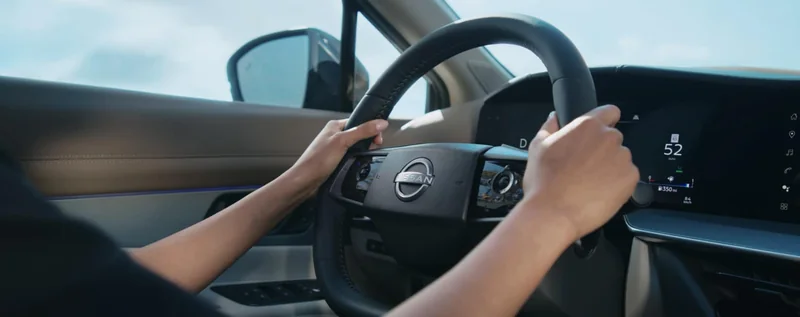 Close view of a Murano driver holding the steering wheel, with driver display visible