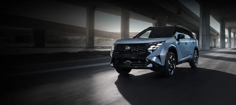 Silver all-new 2027 Rogue Hybrid driving beneath a modern overpass