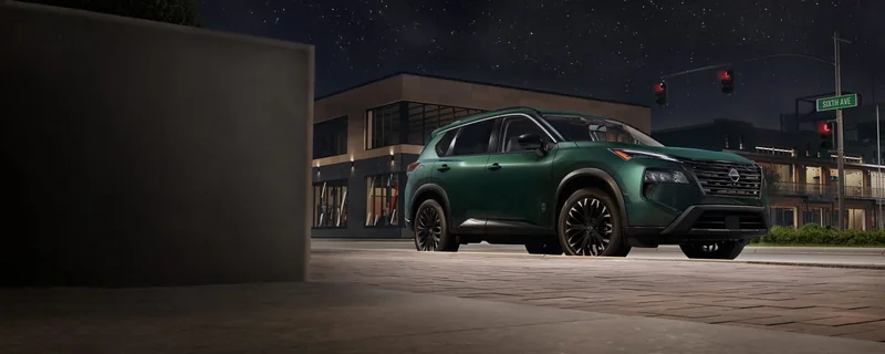 Dark green Rogue Dark Armor parked outside shops at night