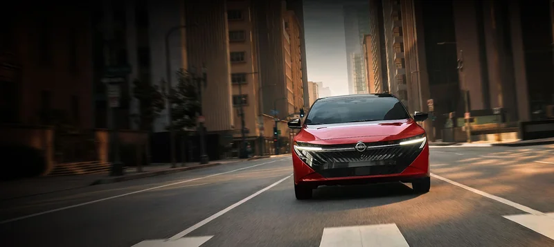 Red all-new Sentra driving toward the viewer on a city street