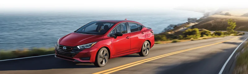 Red Versa driving on a curving coastal road