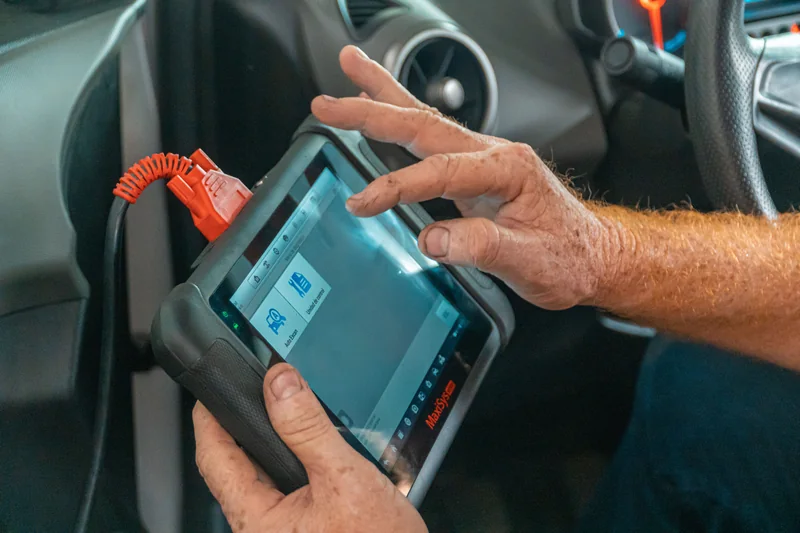 Mechanic using a diagnostic scanner inside a car